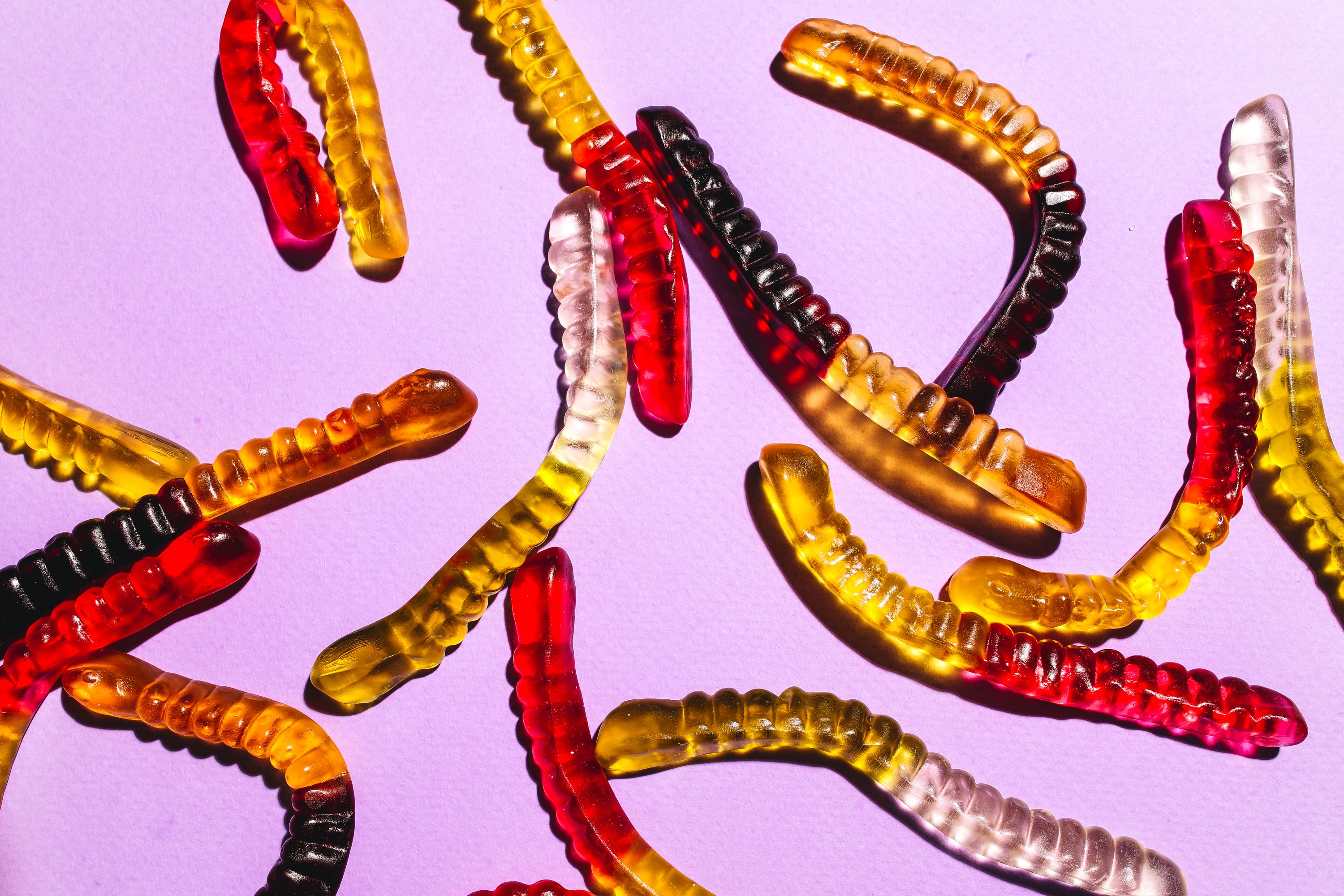 Gummy worms on a light purple background