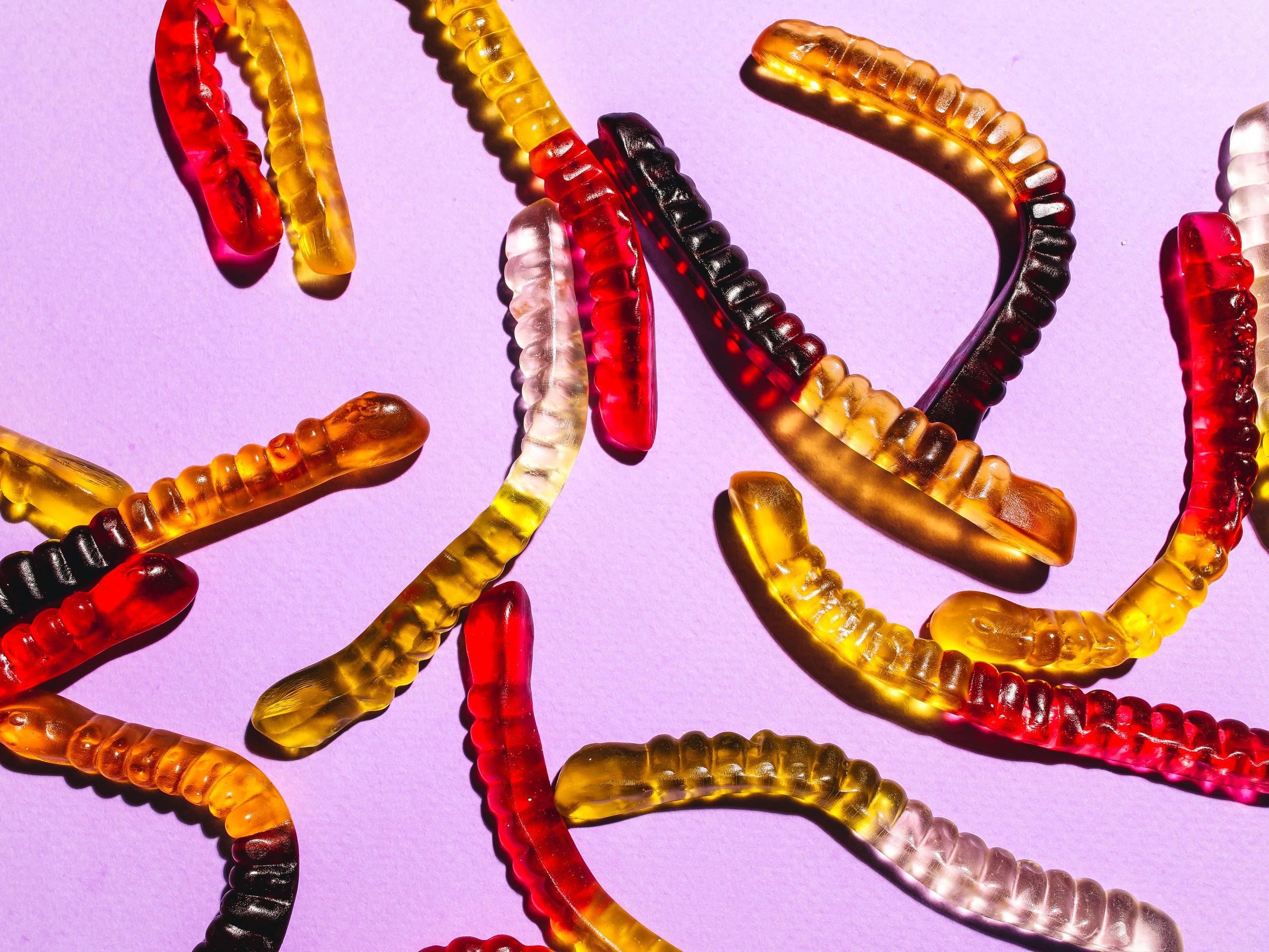 Gummy worms on a light purple background